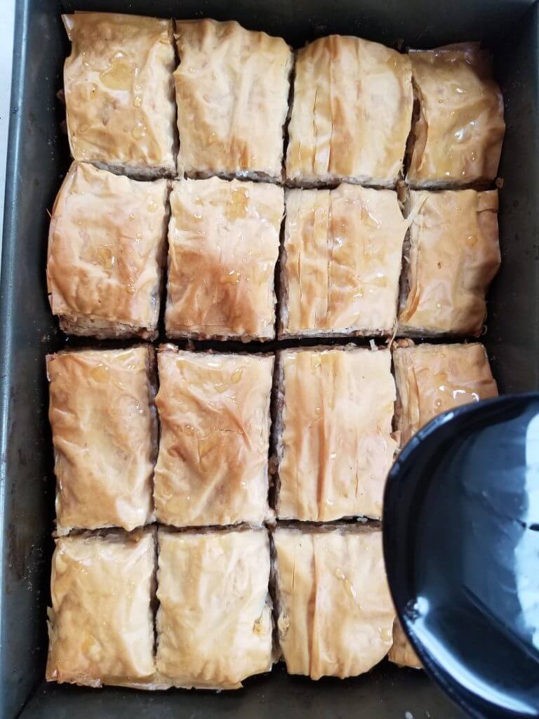 pouring honey mixture over homemade baklava