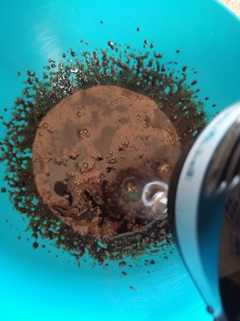 using a hand held blender to beat the boiling water into the instant coffee powder and sugar