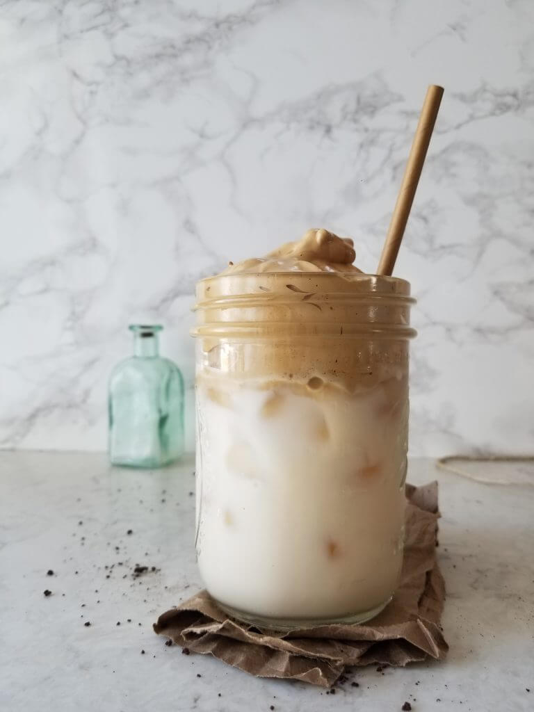 dalgona coffee in a mason jar on a white marble background