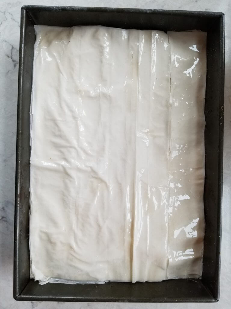 layering the best baklava with walnuts in a pan