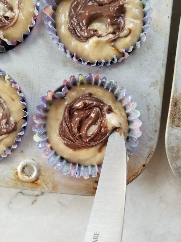 swirling dairy free nutella into the banana muffin with a knife