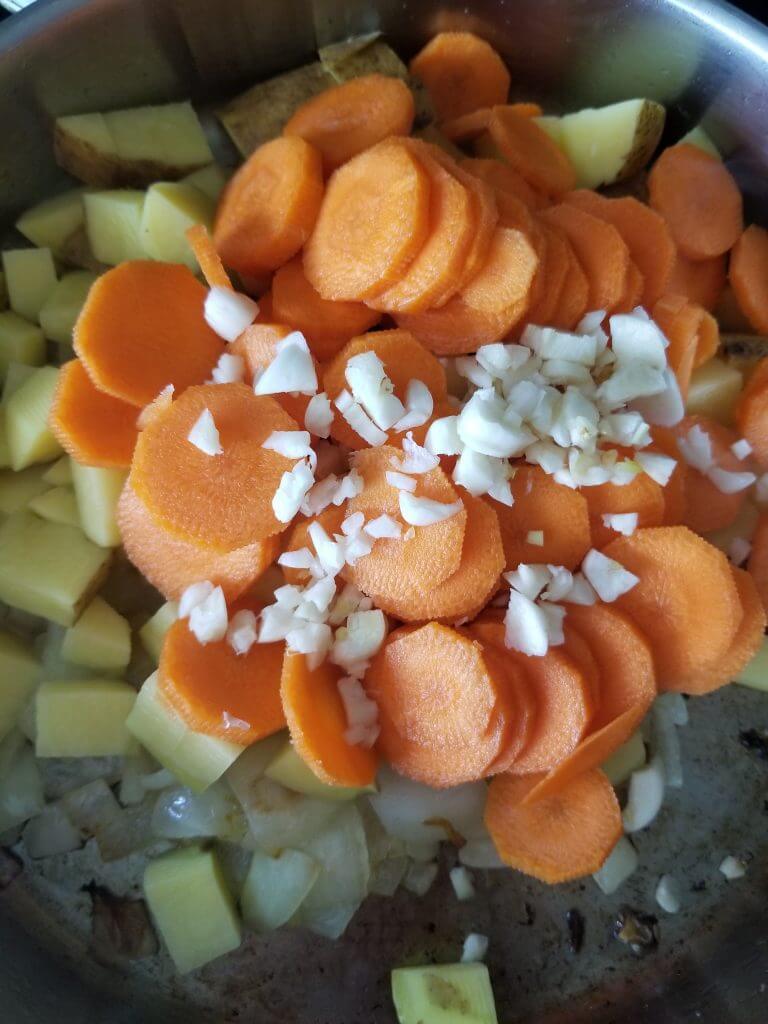 potatoes, carrots, and garlic added to the pan
