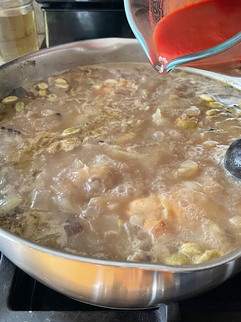 pouring tomato puree into the chicken kabsa broth