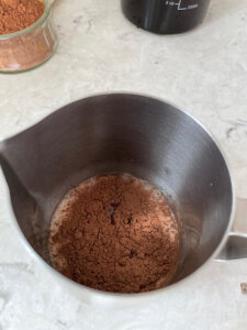 Chocolate cold foam ingredients in a stainless steel milk cup