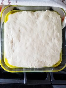 Dough for the ciabatta rolls in a glass square dish