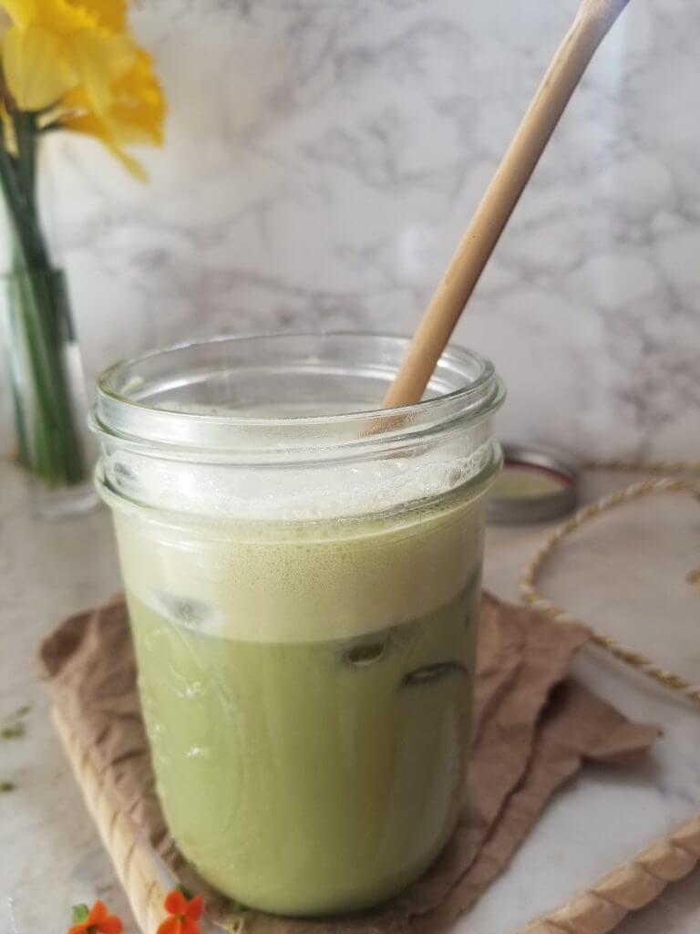iced matcha latte in a mason jar with a bamboo straw