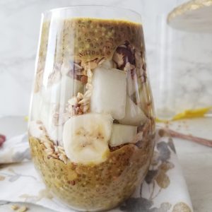 golden chia pudding in a tall stemless wine glass layered with melon and bananas