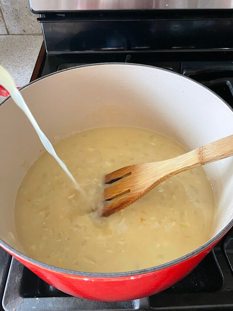 adding bone broth to a pot of soup