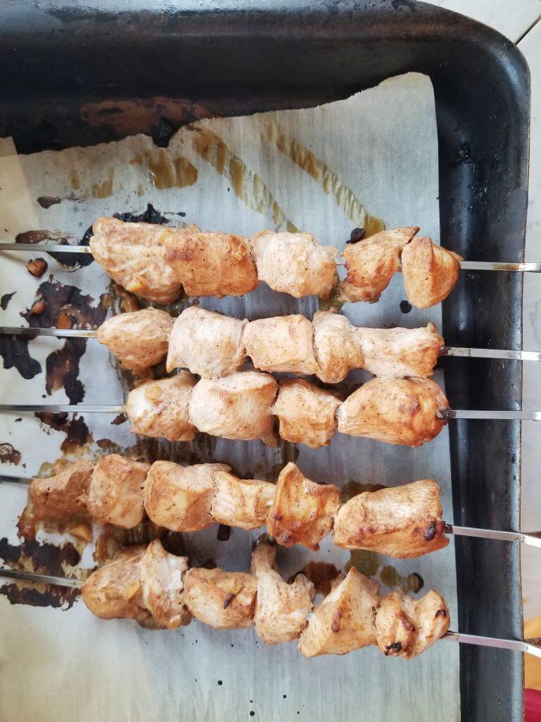 chicken on metal skewers after cooking in the oven