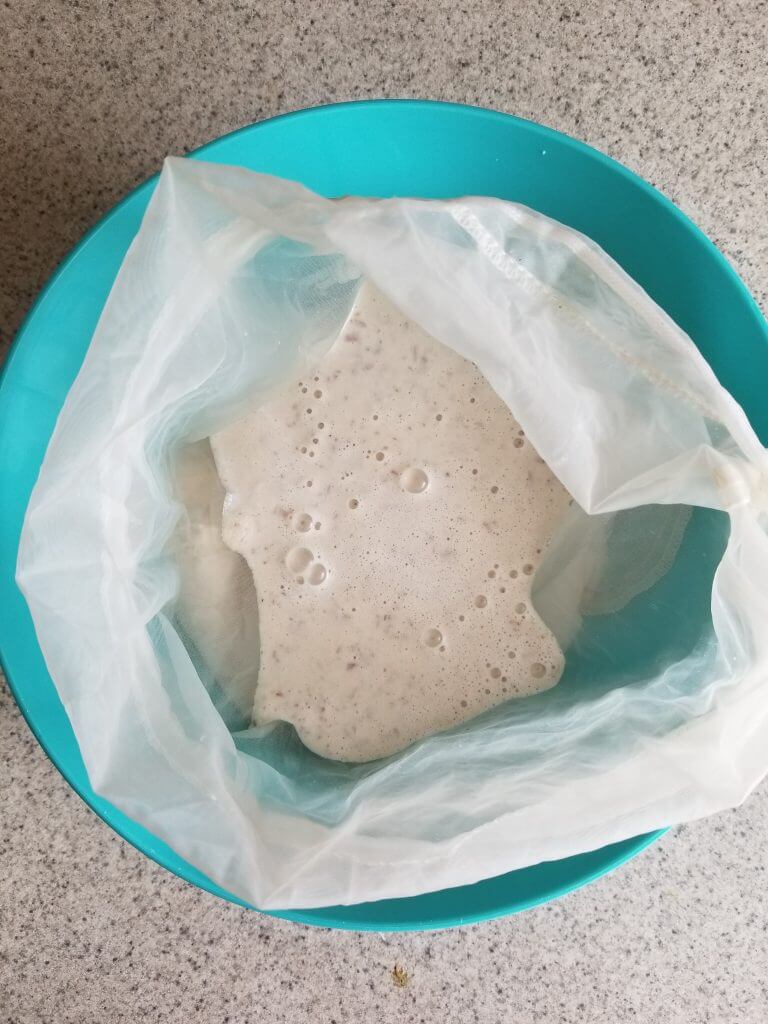 straining homemade almond milk creamer using a nut milk bag