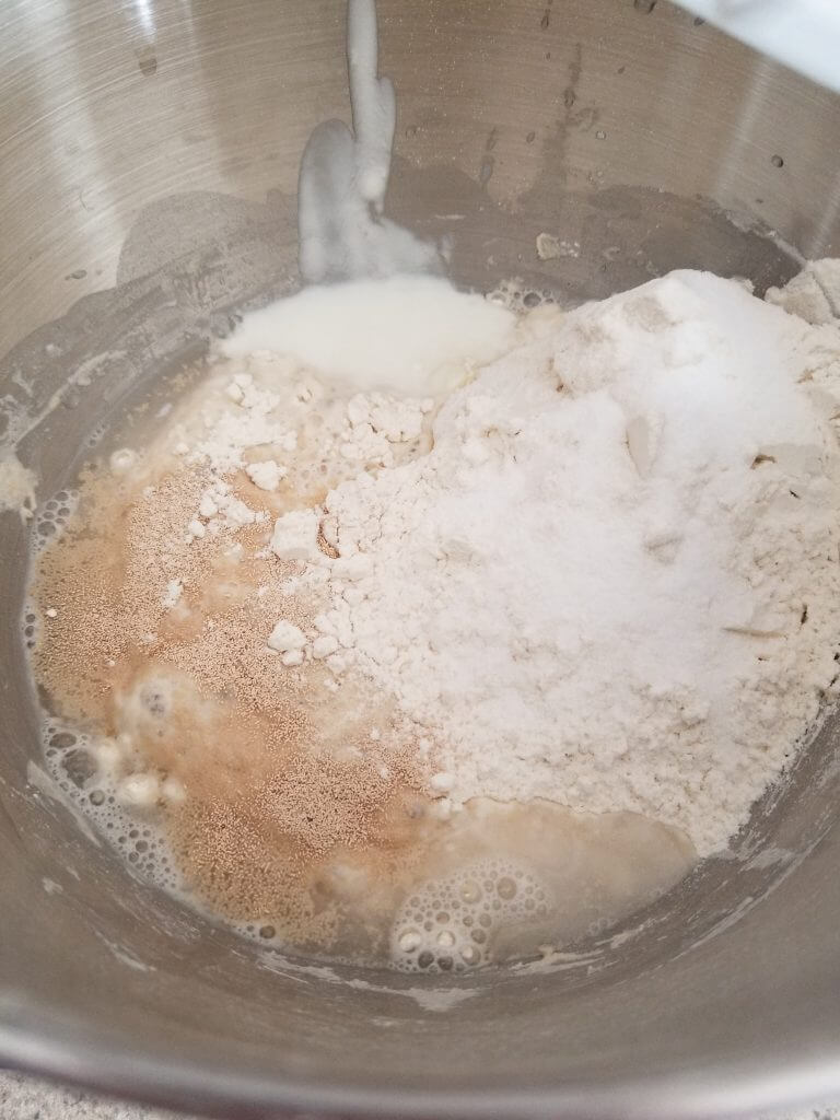 all ingredients for the homemade ciabatta bread recipe in the bowl of a standing mixer before it is combined