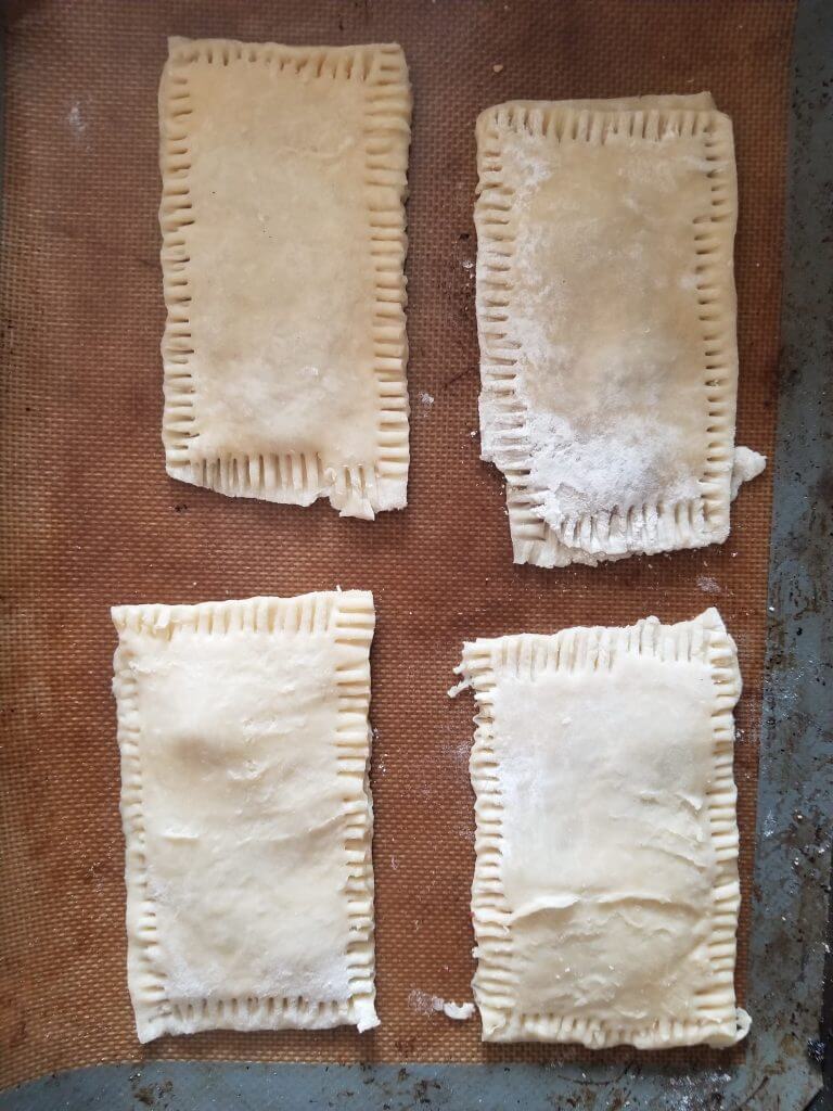 pop tarts on a baking sheet with the edges pressed down with a fork to seal the edges and also give it some texture