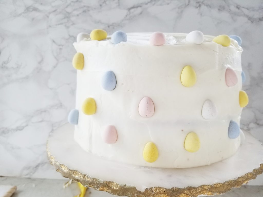 surprise carrot cake before it is cut open to reveal the inside on a gold and marble cake stand
