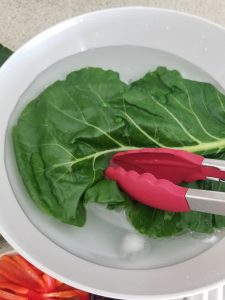 dipping collard green in an ice bath of water to cool it off