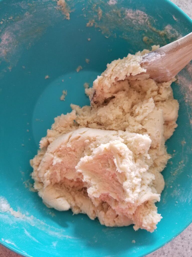 bowl of healthy sugar cookie dough mixed with a wooden spoon