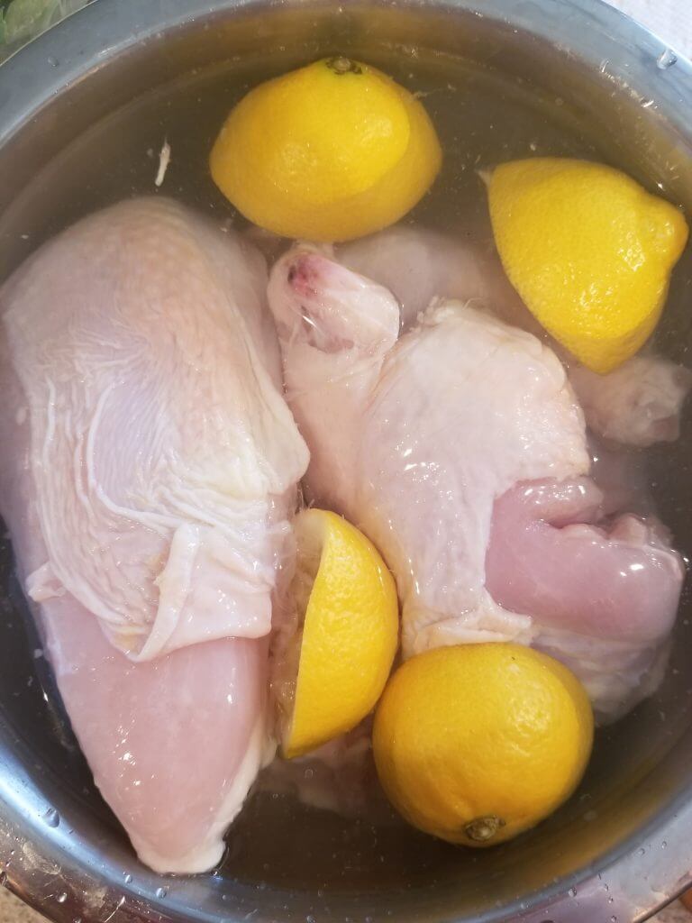 bowl of raw chicken with lemon, vinegar, salt, and water for maqluba