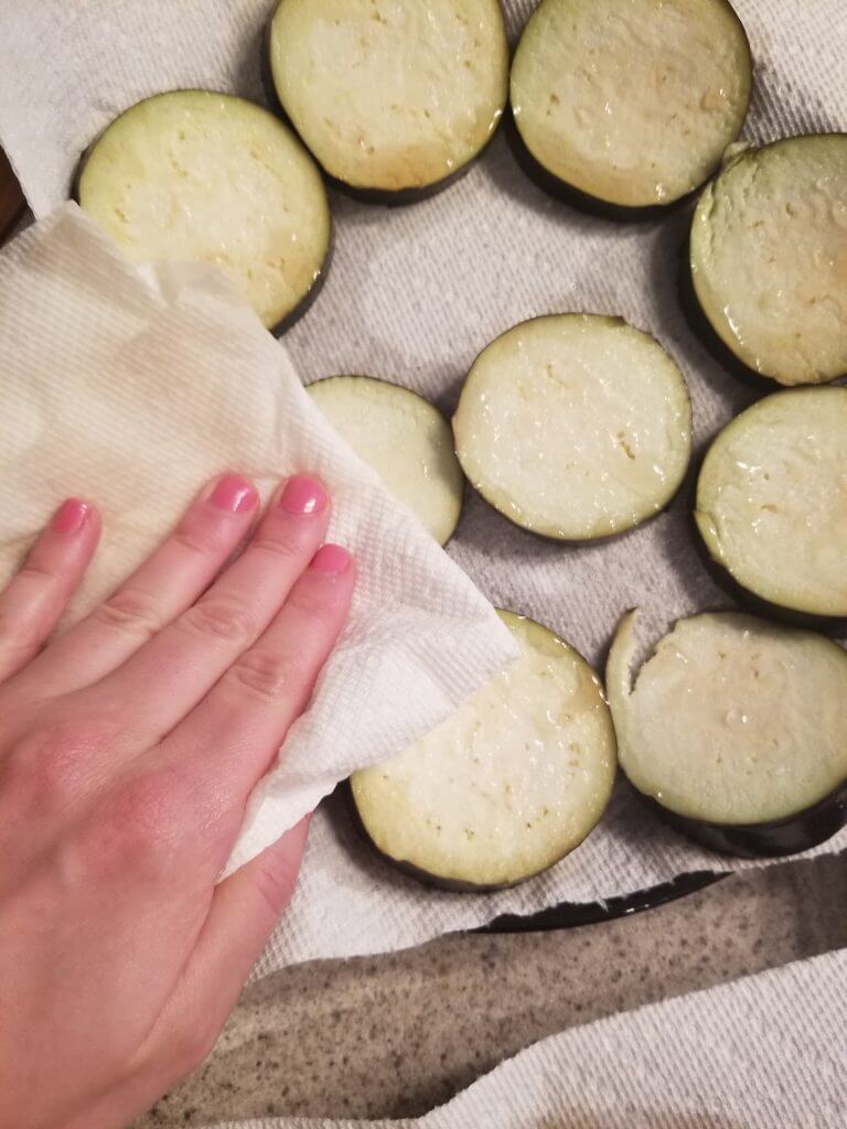 dabbing the water off the eggplant slices with a paper towel