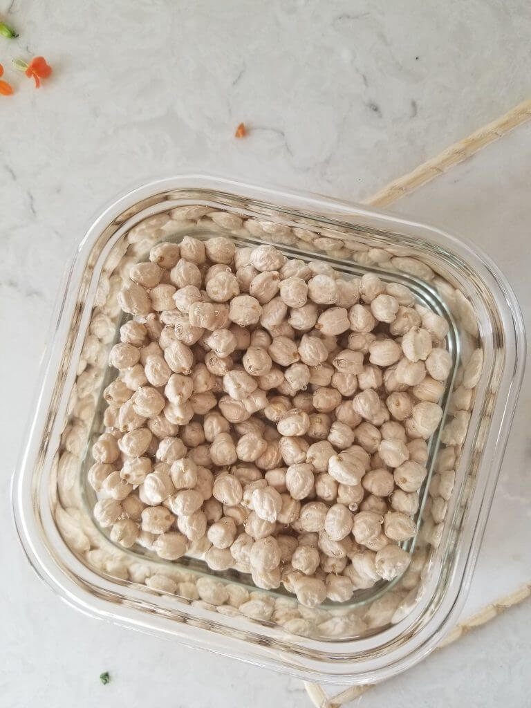 dried chickpeas in a dish with filtered water on them