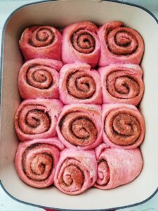 pink cinnamon rolls in pan after baking