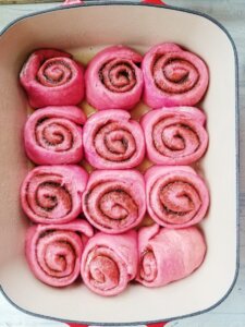 pink cinnamon rolls in pan after rising