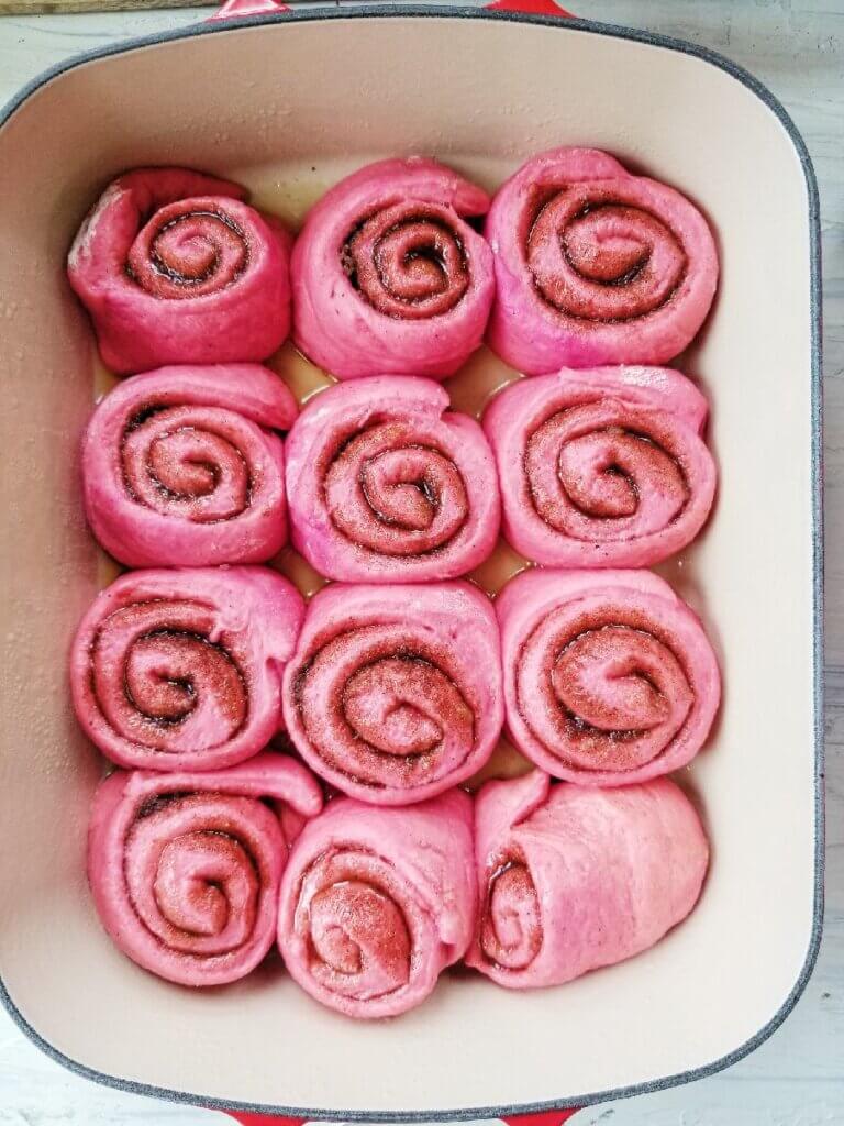 pink cinnamon rolls in pan after rising