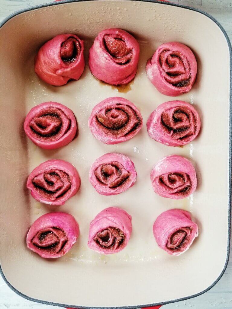 pink cinnamon rolls in pan before rising