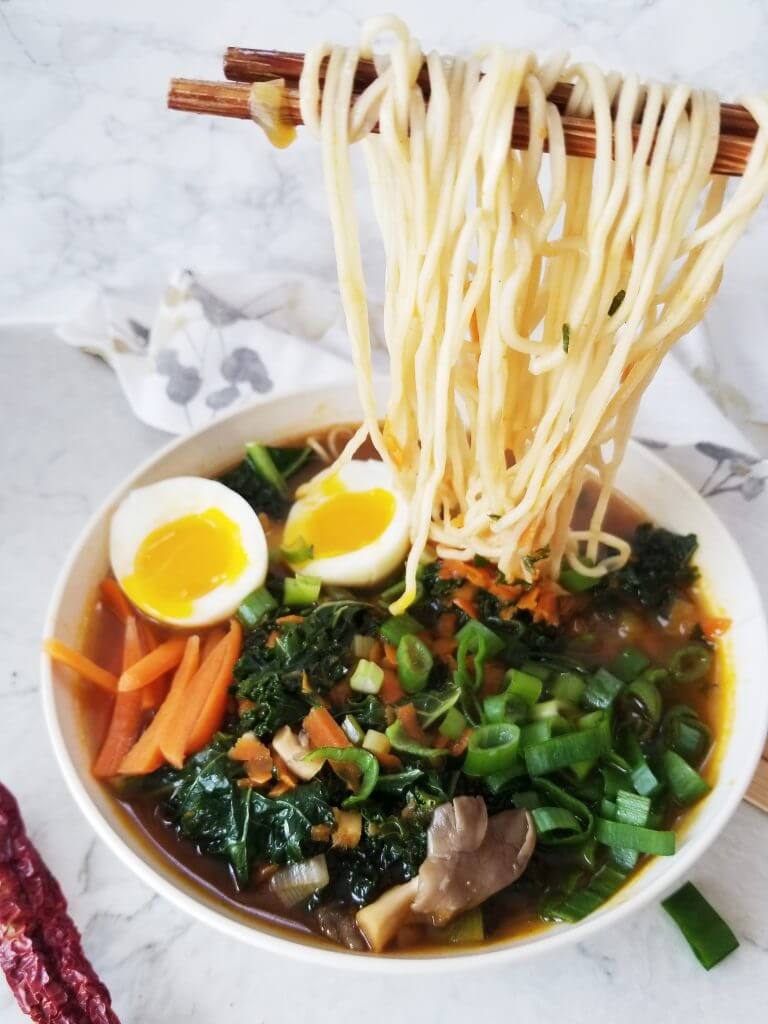 A large bowl ramen noodle soup being eaten with chopsticks