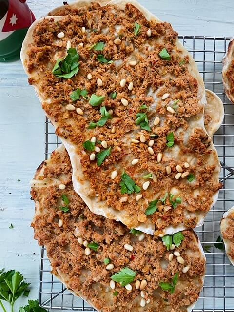 healthy sfiha on a cooling rack topped with pine nuts and fresh chopped parsley