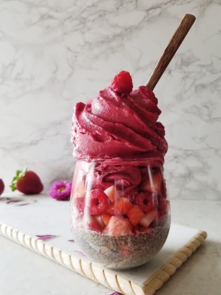 healthy strawberry smoothie parfait with chia pudding and fresh berries in a stemless wine glass