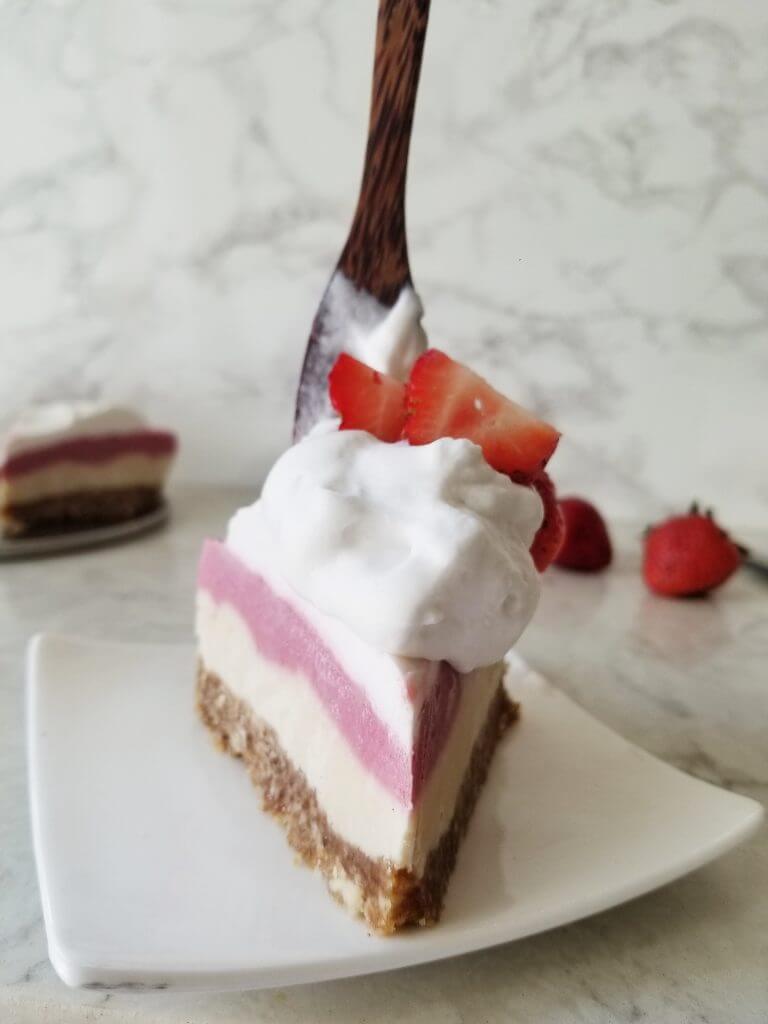 slice of Vegan Strawberry Cashew Cheesecake with coconut whipped cream and fresh strawberries