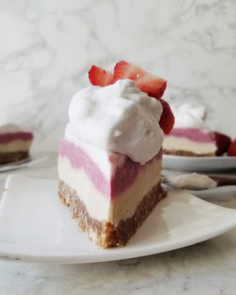 vegan strawberry cashew cheesecake slice with coconut whipped cream and fresh strawberries