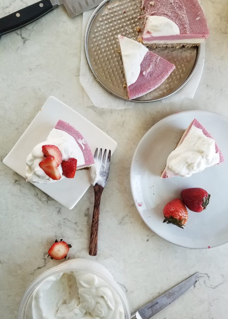 slices of Vegan Strawberry Cashew Cheesecake and coconut whipped cream